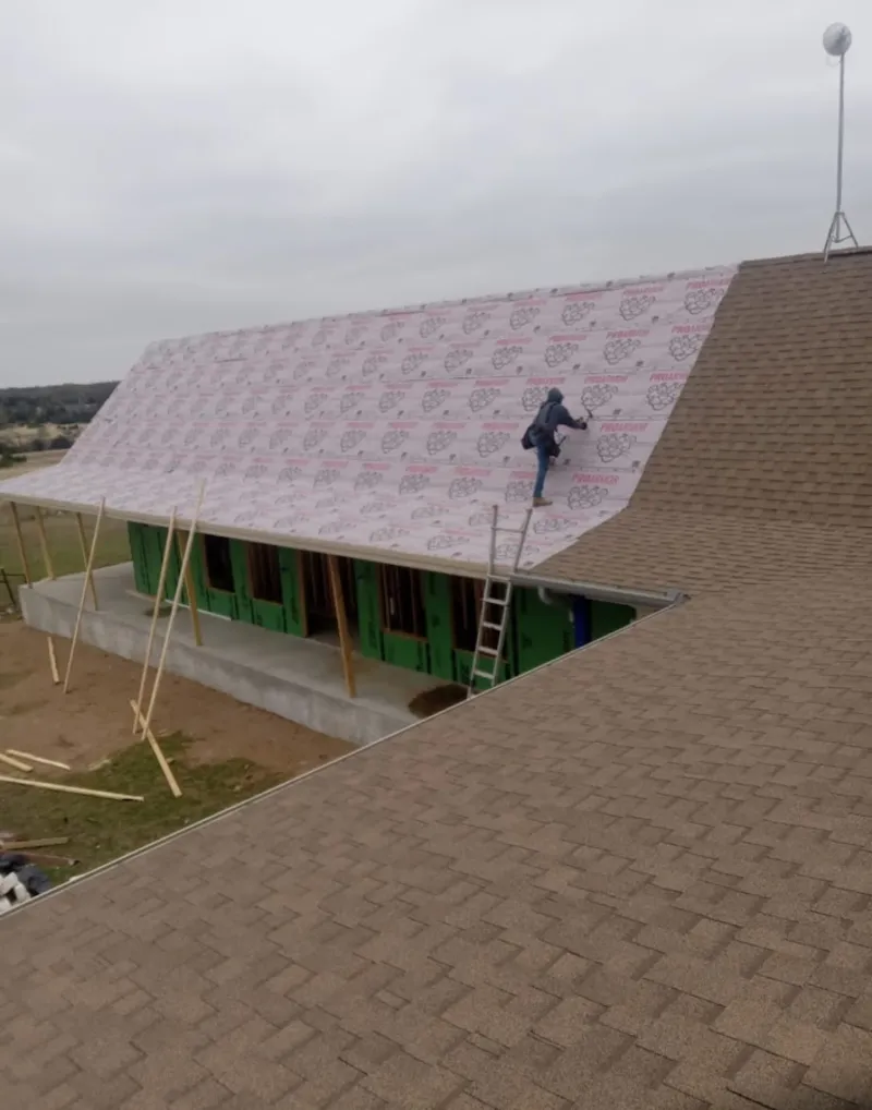 Worker preparing underlayment for a metal roof installation in Winthrop Town